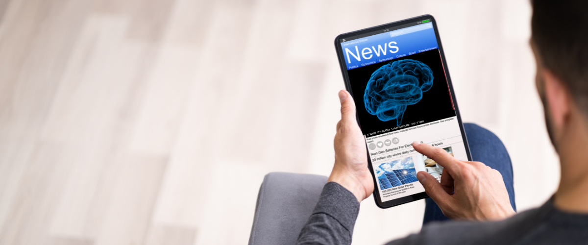 Back of man's head as he's looking at tablet screen with news on it.